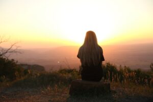 heimwee na verhuizen 13 tips. Foto van vrouw die mediteert bij zonsondergang